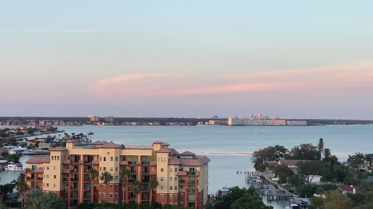Coastal city skyline at sunset with calm sea and warm orange light on buildings, St. Pete Beach Tampa Bay Florida