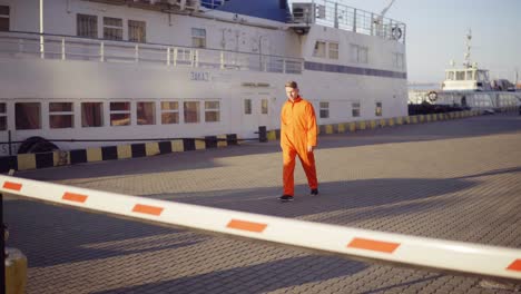 Hafenarbeiter-In-Orangefarbener-Uniform,-Der-Im-Hafen-Durch-Die-Barriere-Läuft