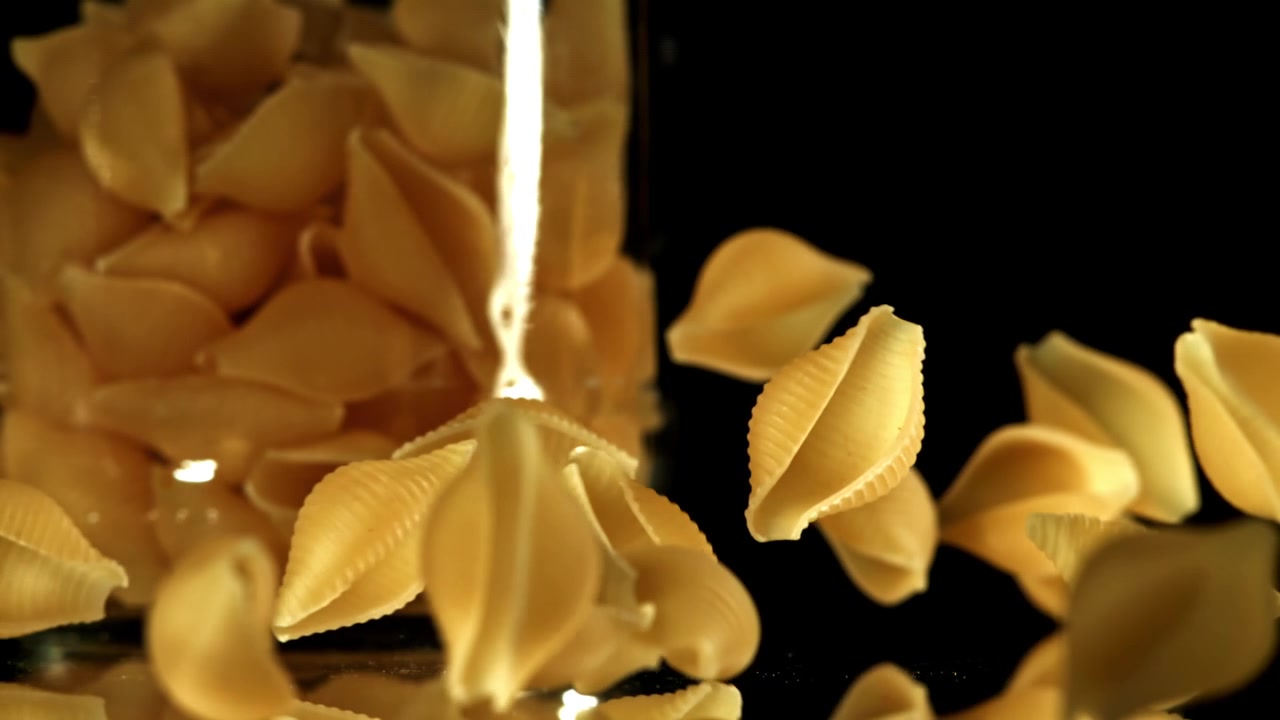 Nahaufnahme: Trockene Conchiglie-Nudeln fallen in Zeitlupe