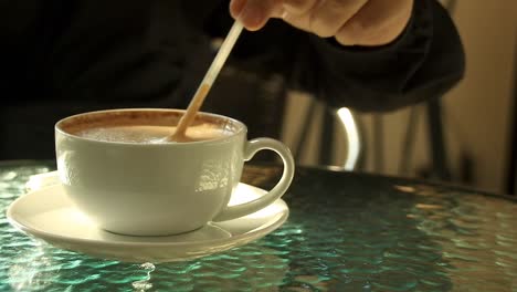 stirring cappuccino at a showing concept of the cozy warmth of the autumn and winter season