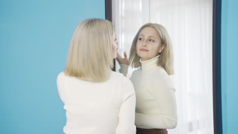 ad woman looking at herself in the mirror at home.