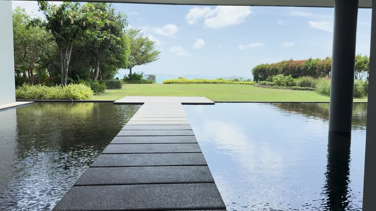 A serene poolside scene at a luxury resort in Phuket, Thailand, showcasing lush greenery and reflective water under bright daylight