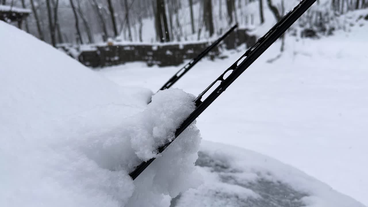 Snow wiper of a car in heavy snow in rural village countryside Iran winter season icy windshield in nature of Hyrcanian forest scenic landscape cabin woods in travel freezing mountain frost cabin