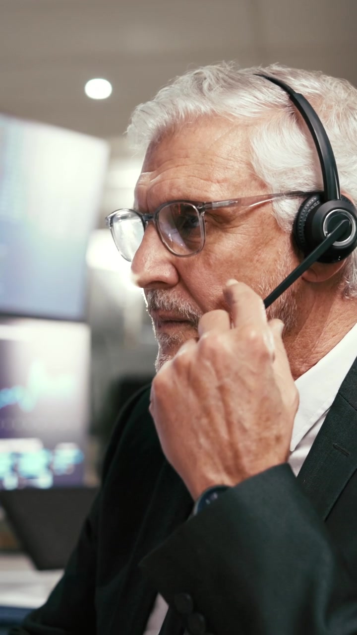 Trader finanziario senior al lavoro alla scrivania in un ufficio moderno
