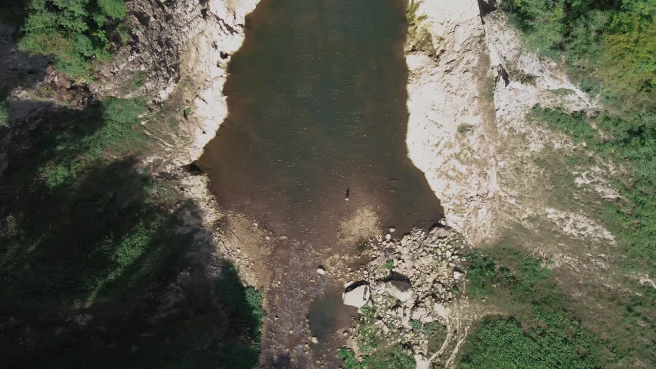 Waterfall in pure wild unpolluted natural mountain landscape with lake in hot springs valley, aerial footage drone top down view