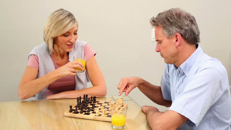 una pareja madura jugando al ajedrez en la mesa.