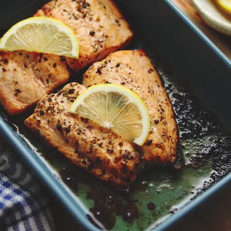 roasted salmon in heat proof dish  with aromatic dill  lemon  salt and pepper on sides