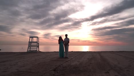 pregnant couple talking at sunset. love concept. romantic couple on sea beach