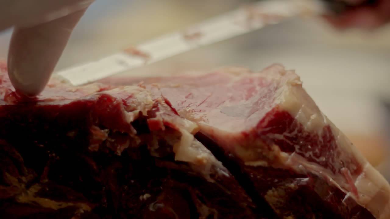An detailed closeup of a whole leg of cured ham resting on a wooden board ready for slicing