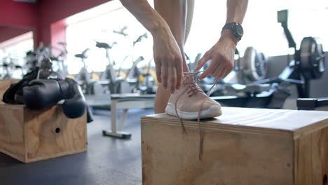 Persona-Atando-Cordones-De-Zapatos-En-El-Gimnasio,-Con-Espacio-Para-Copiar.