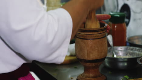 woman crushing and grinding fresh herbs and spices in chalice-shaped mortar