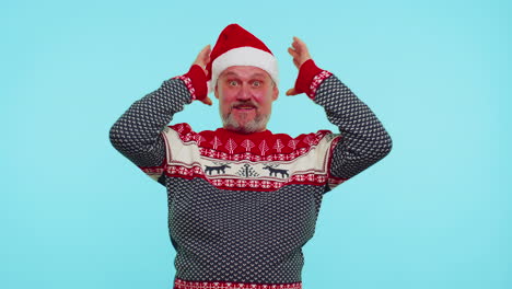 Man-wears-red-New-Year-deer-sweater-raising-hands-in-surprise-shocked-by-sudden-victory,-wow-emotion