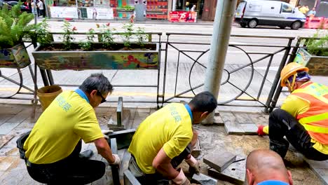 trabajadores que reparan el pavimento en una zona urbana ocupada