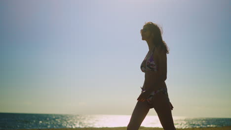 mujer en bikini caminando por la playa