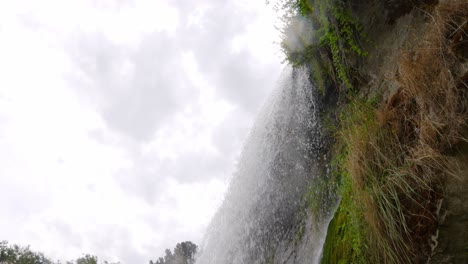 a low angle rolling shot looking up from the base of a waterfall