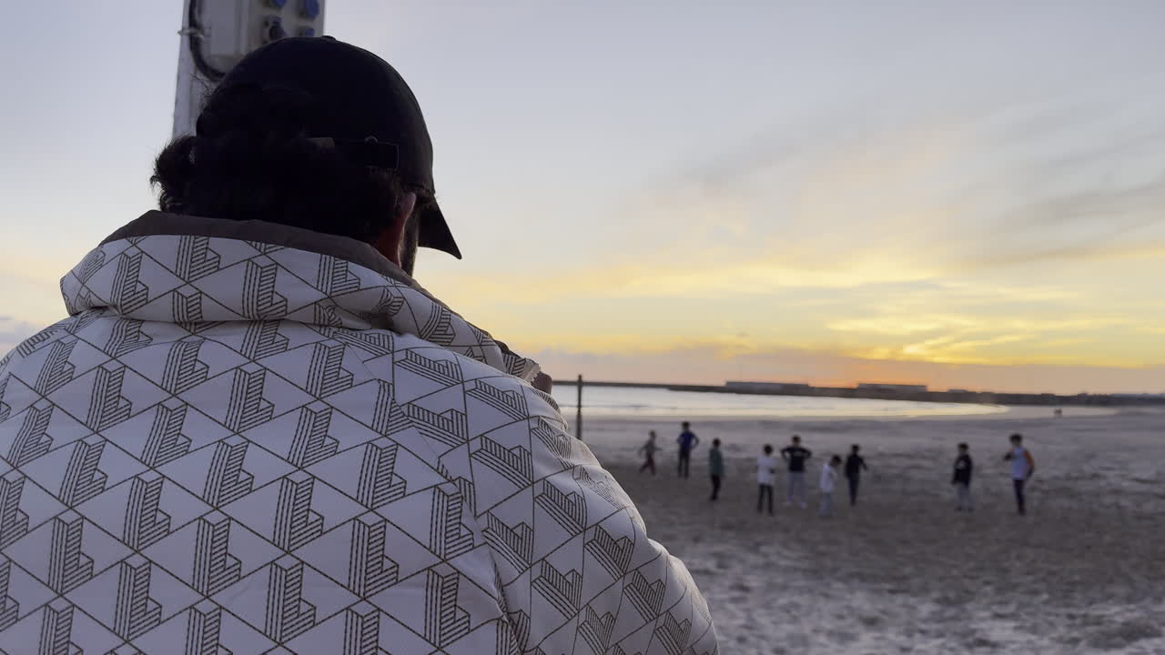 A man records the activities of children playing on the beach
