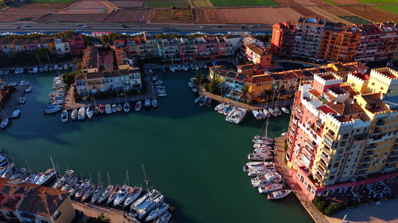 Solnedgangslys over Port Saplaya marina med yachter. Luftfoto af farverige bygninger og sejlbåde i havnen under sent eftermiddagslys i Valencia