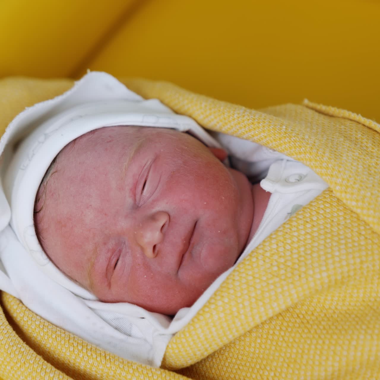 Lovely face of a sleeping newborn coated in blankets. Gloved medic's hands covering the baby after birth. Close up