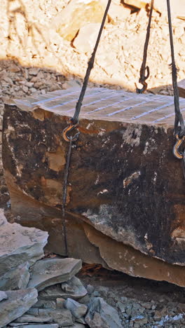 crane lifting heavy rock. heavy natural granite stone blocks stacked for processing vertical video
