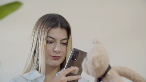 young lady taking picture of teddy bear toy