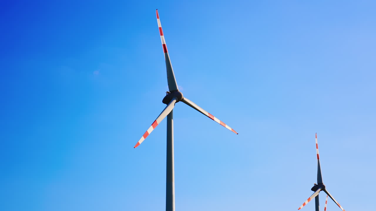 Wind turbines generate clean energy. Wind turbines spin against a clear blue sky, harnessing wind energy to produce electricity in a renewable energy field
