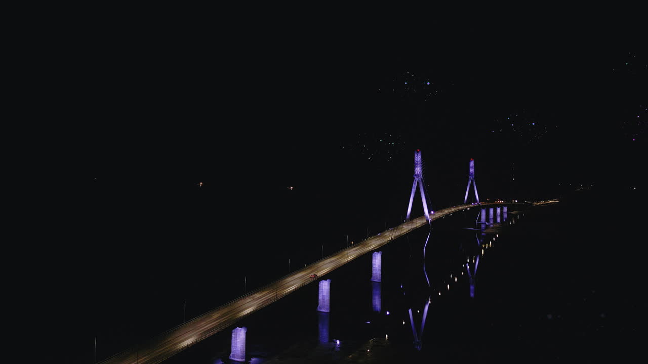 Luci di droni che volano sopra un ponte illuminato sull'acqua di notte