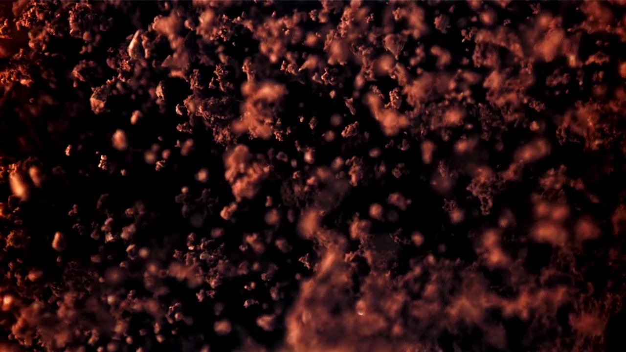 Reddish Particles Floating and Swirling Against a Dark Background