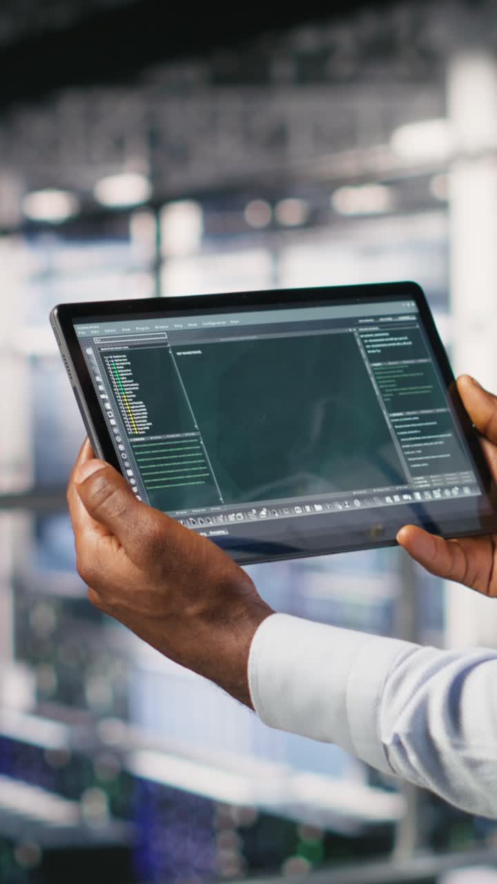 Vertical video Data center admin checking code on tablet next to colleague