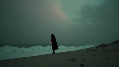 silhouette of a mysterious man approaches the stormy ocean waves with a lantern