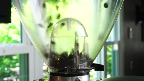 utilizing a top-tier burr grinder to process freshly roasted coffee beans into a medium consistency. pulverizing premium coffee beans in a sleek, industrial-grade black perfect hot cup of hot coffee..