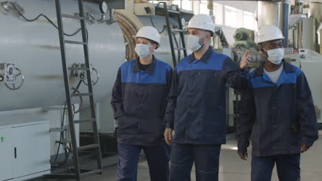 slowmo of supervisor showing workers around plant