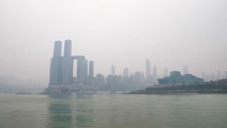 hyperlapse of chongqing’s skyline along the yangtze river, showcasing modern skyscrapers and the iconic theater building, with a misty atmosphere over the cityscape. china