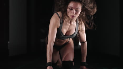 a sexy athletic woman in lingerie dances wet in oil in the gym near the gym near the gym benches and barbells.