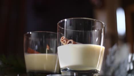 front view of a man adding ground cinnamon to a traditional holiday drink christmas eggnog