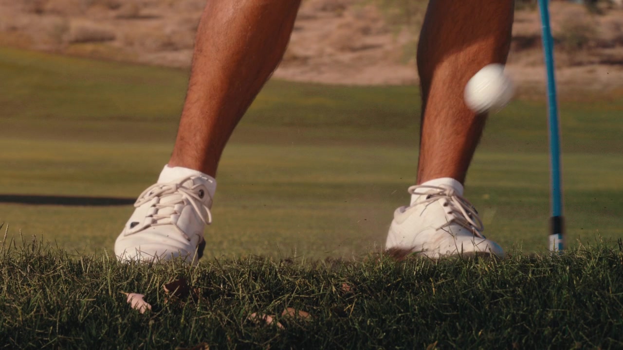 Un golfista colpisce la palla e crea una grande zolla nel rough, ripresa ravvicinata estrema al rallentatore di golf di lato con terra che vola in una giornata di sole in 4k a 800 fps.