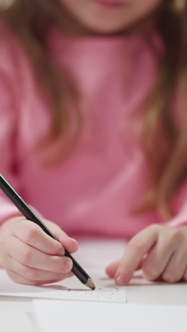Junior schoolgirl writes with black pencil learning English language with African-American teacher at home private lesson closeup slow motion