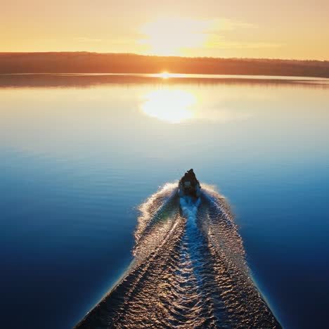 motor boat floating on the river at sunset. path on water after motion of motor boat on the background of a setting sun.