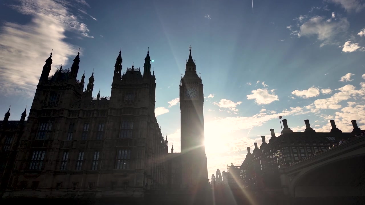 Cung điện Westminster và Tháp Elizabeth tạo thành một bóng đen khi mặt trời chói chang lóe sáng phía sau chúng từ góc nhìn của một chiếc thuyền đang di chuyển chậm