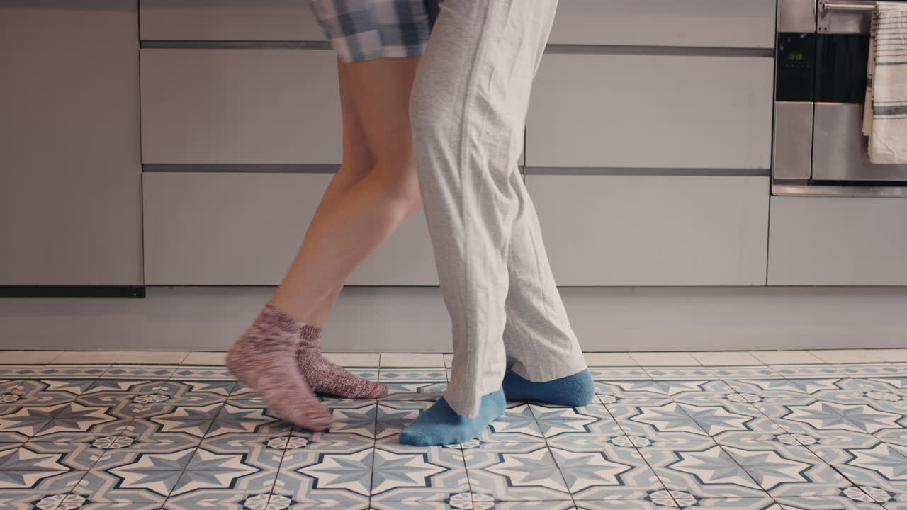 una feliz pareja de recién casados bailando en la cocina con pijama por la mañana en casa enamorados