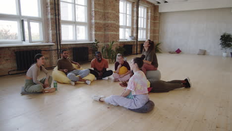 young multiethnic people resting and chatting after dance class