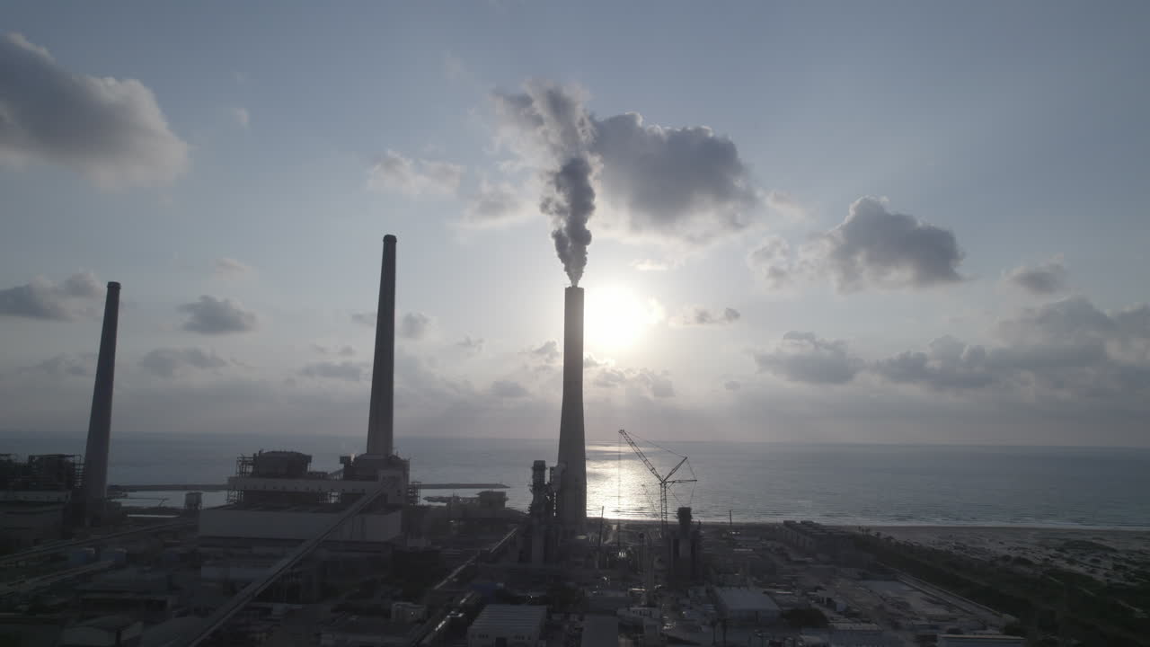 Aerial view of a power plant with 4 chimneys, one of which emits thick smoke into the air, polluting energy in Israel