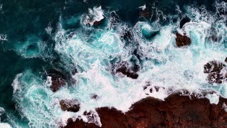 Ein-Blick-Aus-Der-Vogelperspektive-Auf-Eine-Felsige-Küste-Mit-Wellen,-Die-Auf-Die-Felsen-Und-Das-Meer-Schlagen