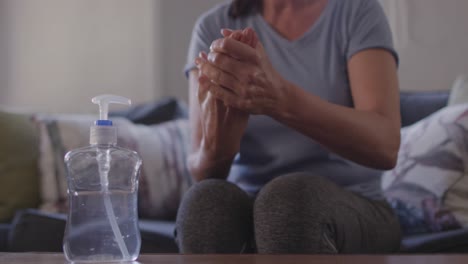 sección media de una mujer desinfectando sus manos en casa