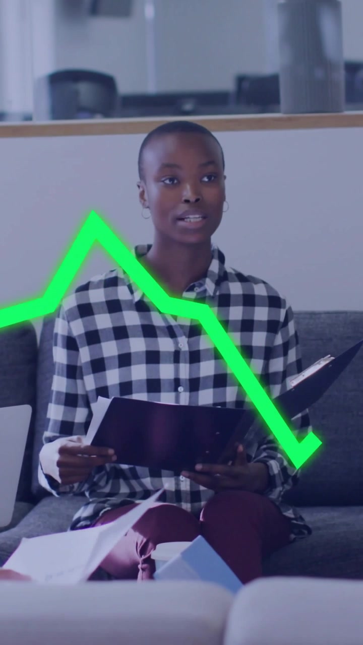 Donna in camicia a quadri che riceve documenti e legge dati in un salotto, con una cartella nera e un grafico al neon.