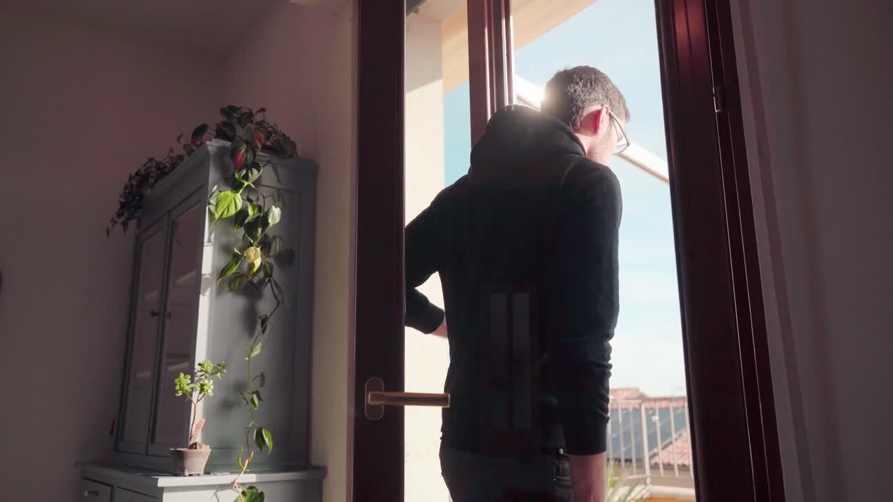 joven abre la puerta de la terraza