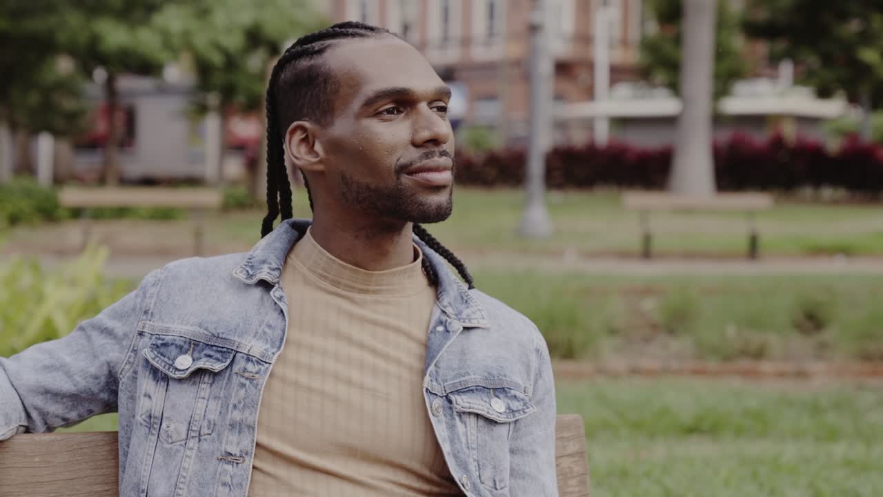 Man with dreadlocks sitting on a park bench