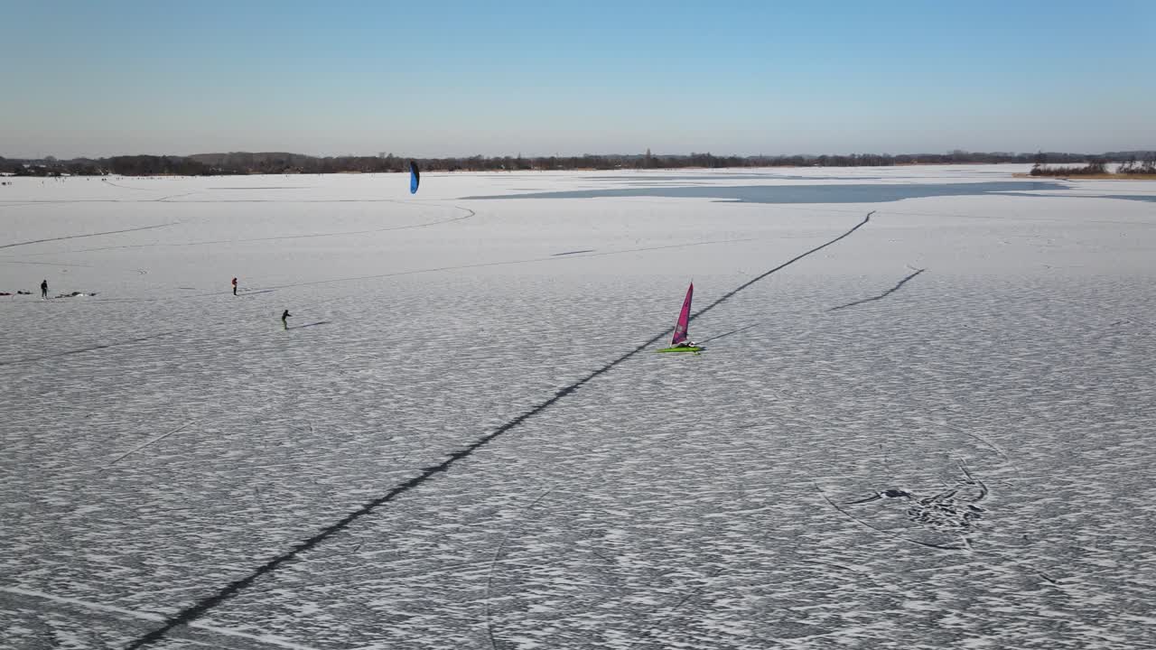 Aerial tracking shot of Sailing Ship Yacht Skates On frozen Iced Lake during sun in winter