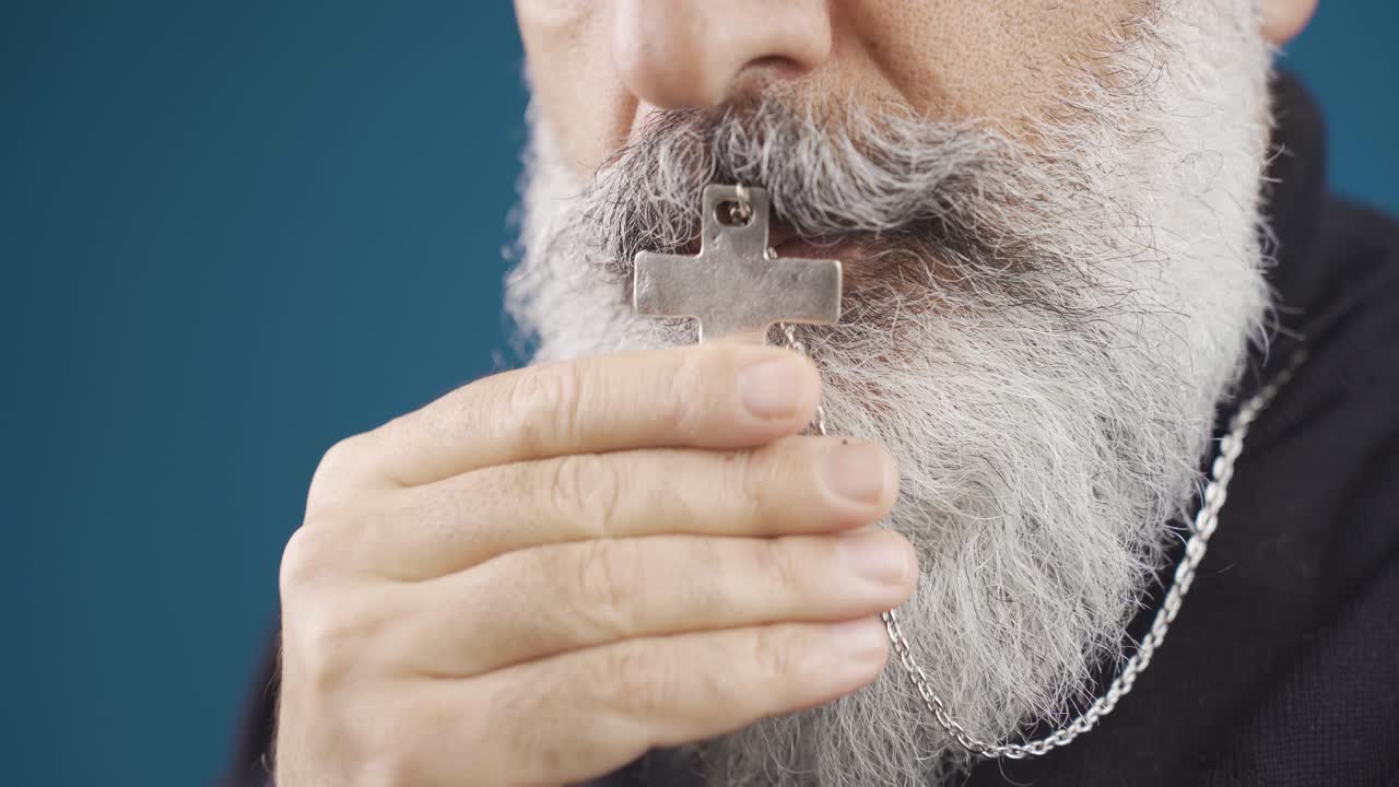 십자가 목걸이를 들고 존경하는 기독교인 남자.