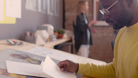 Side-View-Of-A-Focused-Man-Sitting-At-Drawing-Desk-And-Working-On-A-New-Project-In-An-Animation-Studio-2