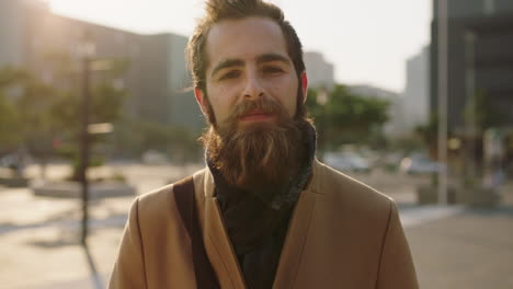 portrait of attractive young bearded hipster man looking pensive thoughtful at camera in urban city background sunset